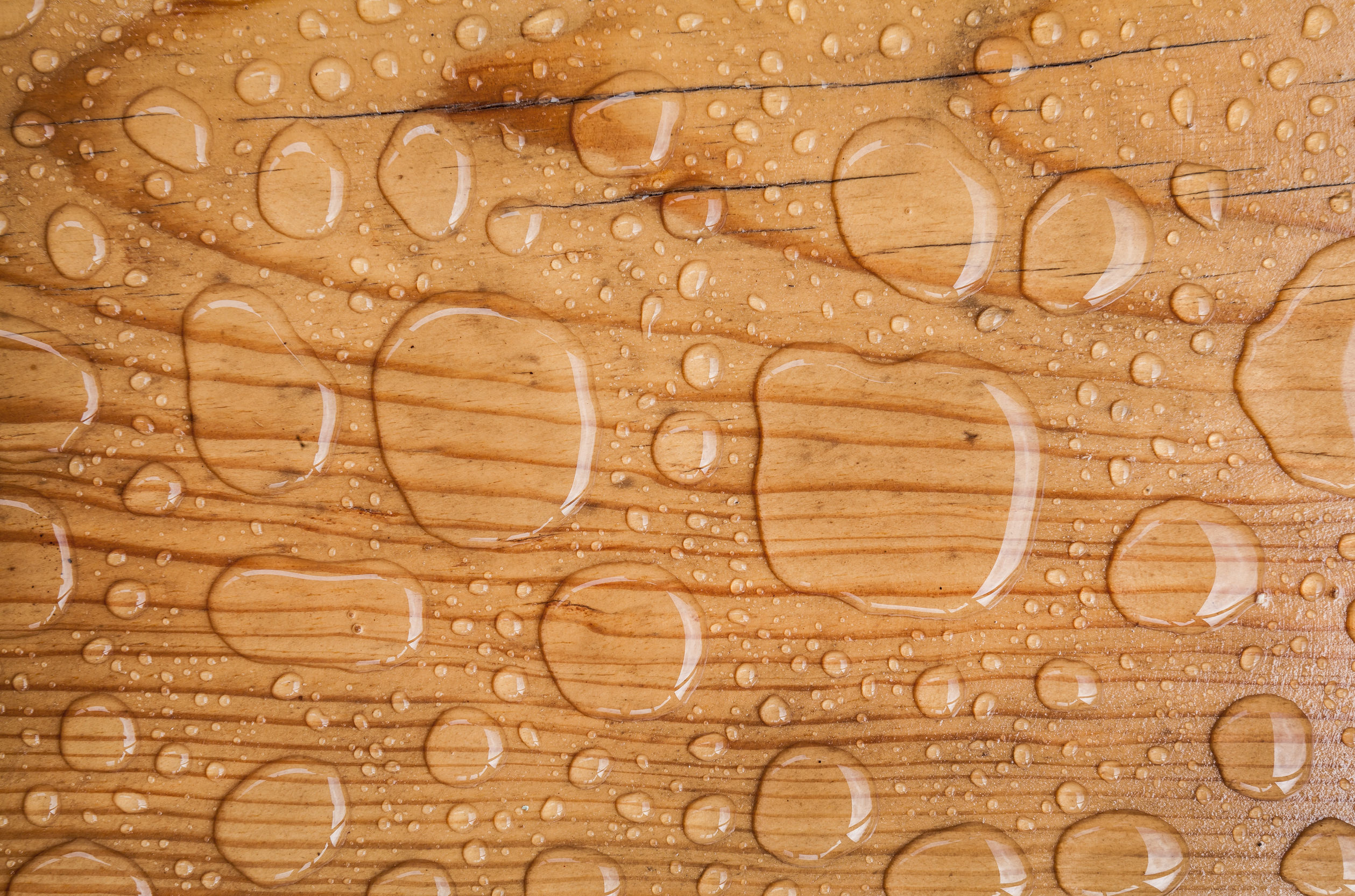 water drop A close-up of a wood floor with water drops on it.